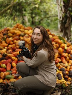 Nathalie filming in front of a pile of cocoa pods